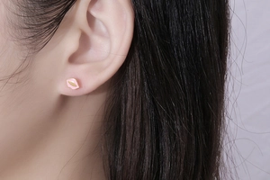 Close-up of a mini pink lips stud earring in gold plated titanium steel on a model's ear