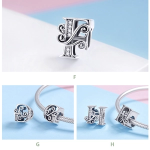 Macro detail of 925 sterling silver charms with zircon inlay for letter styles F, G, and H