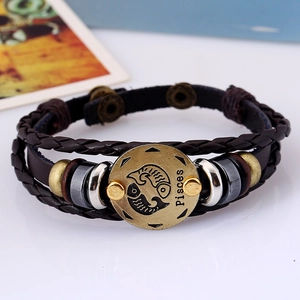Detail of woven brown leather bracelet with Pisces zodiac alloy charm and layered texture