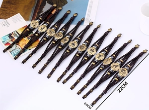 Detail view of woven brown leather bracelets with bronze zodiac charms and snap closure