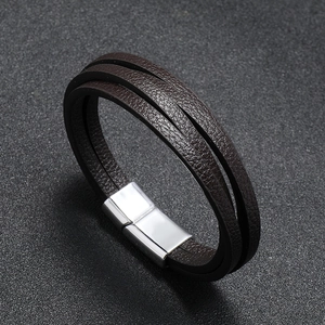 Detailed macro view of multi-layer brown leather bracelet with silver magnetic metal clasp