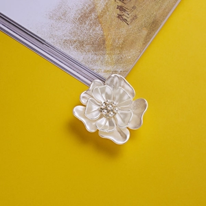 Élégante broche fleur de camélia blanc avec perles et cristaux sur fond jaune