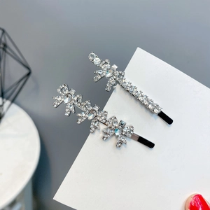 Detailed close-up of two silver alloy bow hair clips with shiny zircon and rhinestones