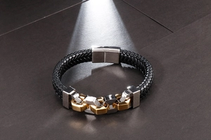 Detailed view of men's black braided leather bracelet with gold and silver metal links
