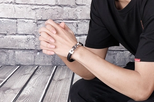 Detail of men's woven black leather and silver steel chain bracelet on a wrist
