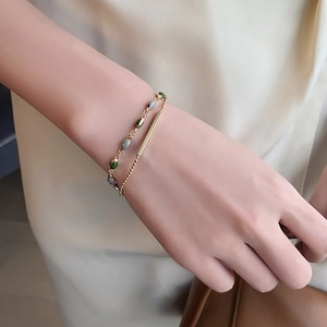 Bracelet double couche plaqué or avec pierres ovales vertes et grises sur poignet