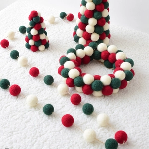 Detail of wool felt Christmas tree ornaments and wreaths in festive red, green and white
