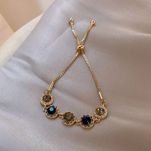 Macro shot of gold-plated adjustable bracelet with blue stones on beige satin cloth