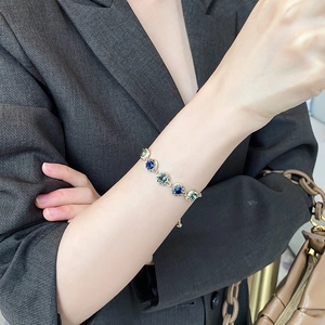 Detailed shot of a gold-plated bracelet featuring blue and grey-green faceted crystals