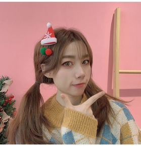 Modèle portant une barrette chapeau de Noël et des pinces à pompons colorées