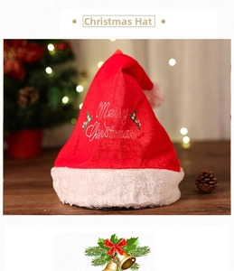 Close-up of plush red Christmas hat with Merry Christmas embroidery on a festive wooden table