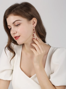 Boucles d'oreilles longues dorées avec cascade de roses rouges portées par un mannequin
