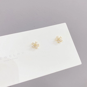 Close-up of gold flower earrings with clear zircon stones on a jewelry display card