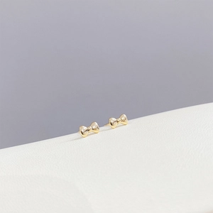 Elegant gold bow earrings set with sparkling zircon in a minimalist luxury style