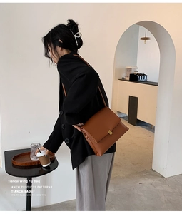 Dettaglio di una borsa a tracolla vintage marrone con fibbia dorata su un modello