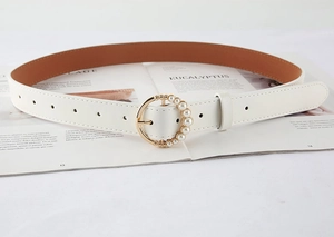 Detail of white leather belt featuring a gold circular buckle with elegant pearl inlay