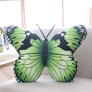 Detail of green butterfly plush pillow with realistic wing texture on a soft sofa