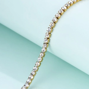 Close-up of golden tennis bracelet with sparkling zircon stones in four-prong settings