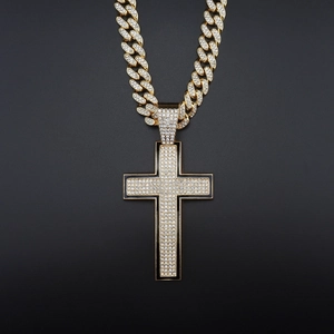 Close-up of gold iced-out cross pendant with black enamel on a Cuban link chain
