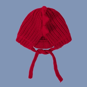 Detail of red knitted baby dinosaur hat with decorative 3D spikes and braided ties