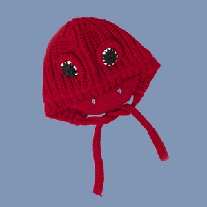 Detail of red knit kids dinosaur hat with monster teeth and ear flaps with ties