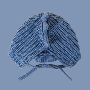Close-up of blue knitted baby dinosaur hat with spikes and soft chin straps