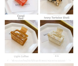 Detail of four acetate claw clips in coral, tortoiseshell, coffee and cream on a ceramic tray