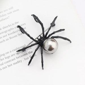 Detail of a black spider brooch with a silver-grey pearl on a vintage book page