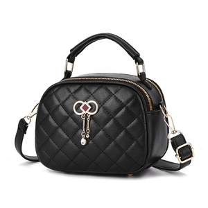 Elegant black quilted handbag with golden bow hardware and crystal pendant