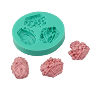 Detail of green silicone mold and three pink baby shape fondant figures for cake decoration
