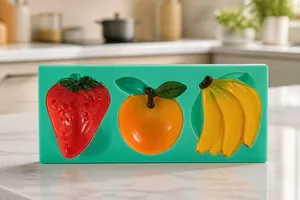 Detailed view of green silicone mold with strawberry, apple and banana fruit shapes
