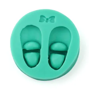 Macro detail of mint green silicone mold featuring two 3D baby shoe shapes with bows