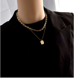 Close-up of double-layered gold stainless steel necklace with engraved rectangle pendant