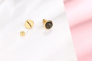 Macro detail of gold-plated titanium earrings with crackle marble inlay and screw back