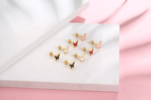 Macro view of screw-back butterfly stud earrings in black, white, red, and pink colors