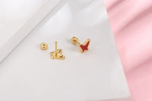 Detail of red enamel butterfly stud earrings with secure gold screw back design