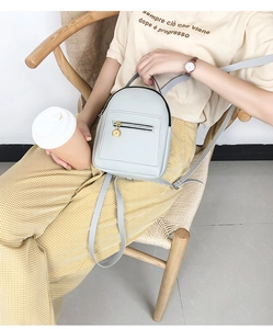 Mini grey PU leather backpack with zip pocket shown in a lifestyle casual setting