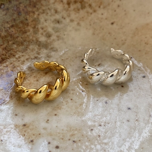 Close-up of gold and silver twisted rope rings on a textured ceramic surface