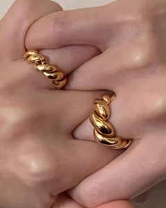 Close-up of dual-layered twisted rope rings in gold finish worn on interlocked hands