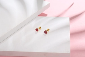 Close-up of red heart earrings with golden metal base and secure screw-back design