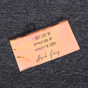 Detail of holographic orange PVC pouch with black zipper and funny printed text