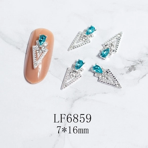 Macro shot of 7x16mm silver V-shape nail jewelry with blue teardrop gemstone and crystals