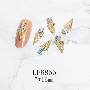 Macro detail of 7x16mm 3D gold alloy nail charms with AB rhinestones on marble background