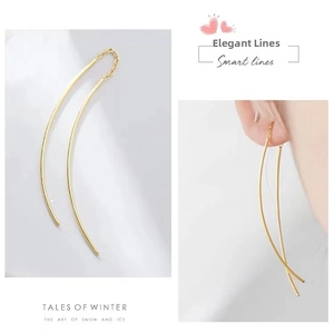 Detail of elegant gold tassel earrings featuring curved lines and minimalist chain links