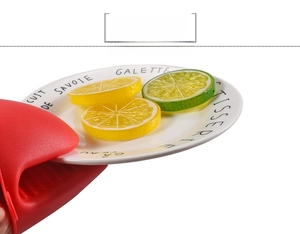 Detail of red silicone heat resistant pinch mitt gripping a white ceramic plate