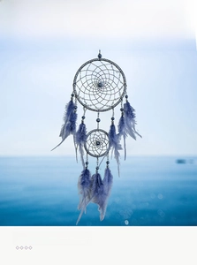 Detail of a purple double-hoop dreamcatcher with feathers and blue beads in focus