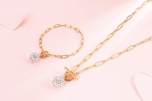 Detail of gold paperclip chain necklace and bracelet set with crystal ball charms and OT clasp