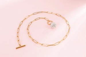 Detailed view of a gold square link chain necklace with a crystal-encrusted ball pendant