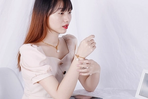 Close-up of gold box chain necklace and bracelet set featuring round white pearls on model