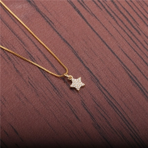Detail of a gold star pendant necklace with cubic zirconia on a brown leather texture